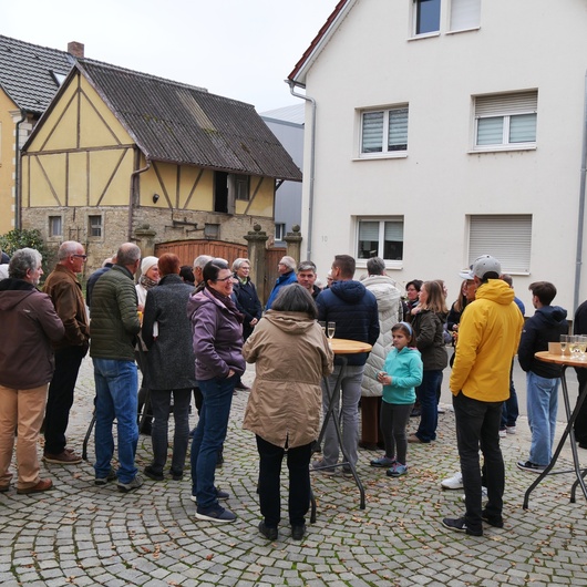 Auf dem Platz vor der Kirche stehen Menschen beieinander und unterhalten sich.